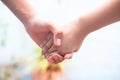 Female childÃ¢â¬â¢s hand holding the hand of elder male shot with a bokeh background and horizontal.